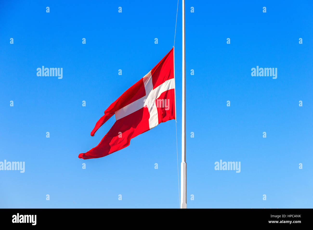 Danish flag at half-mast on a sunny day Stock Photo