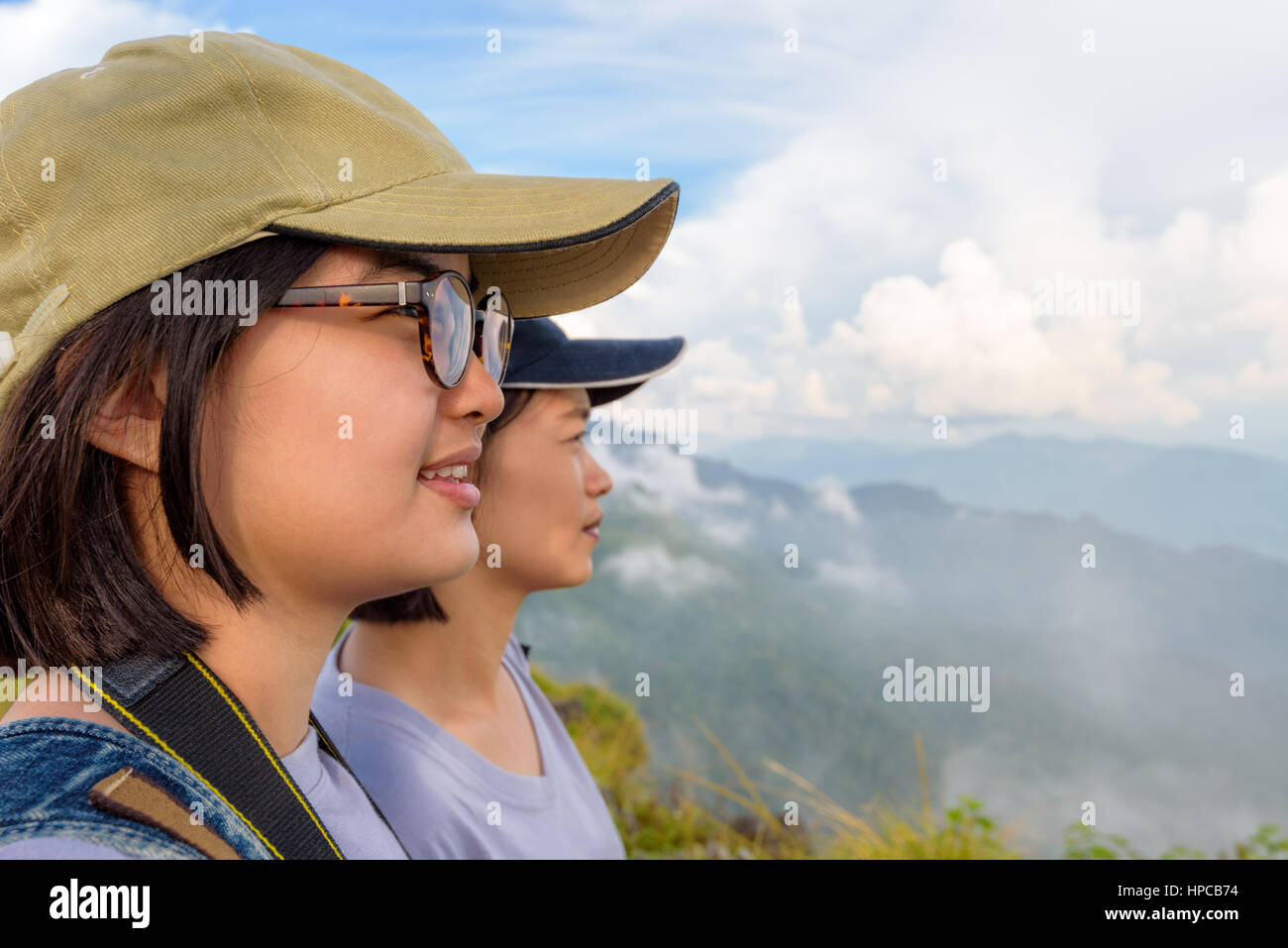 Face two young women hiker, mother and daughter smiling happily while looking beautiful landscape nature of mountain range and sky at Phu Chi Fa Stock Photo