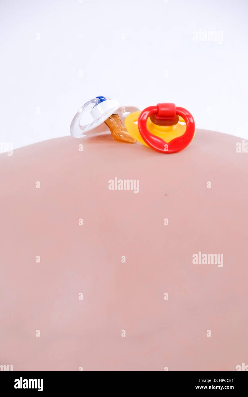 Model released , Kinderschnuller am Babybauch - dummies on baby belly Stock Photo