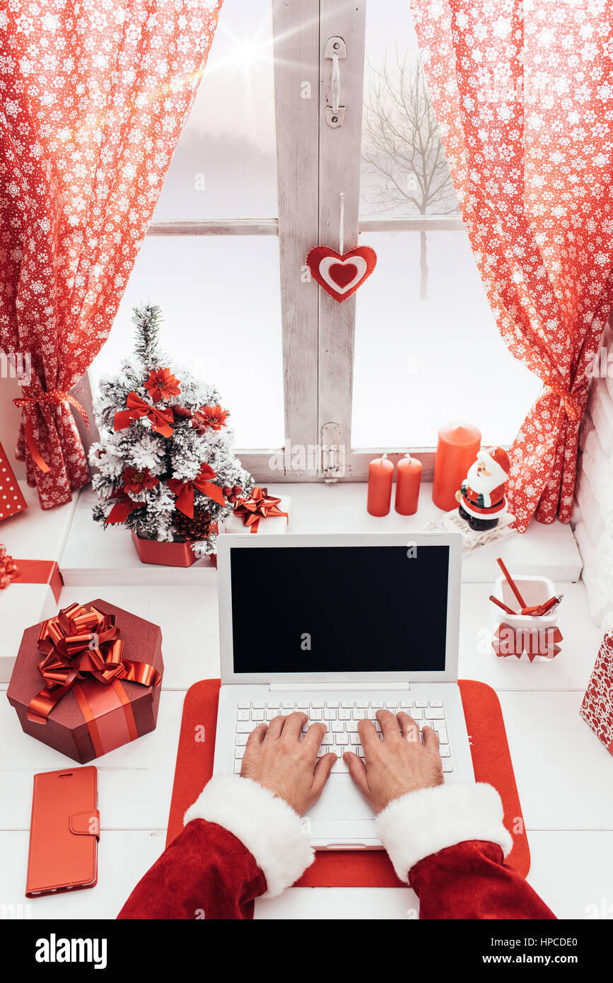 Santa working at desk and networking with a laptop, he is connecting to ...