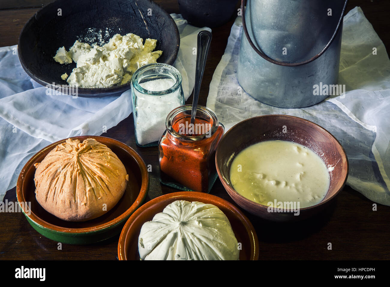 home made cheese over a rustic wooden table with its ingredients, milk, salt, paprika, curd and an old milk churn Stock Photo