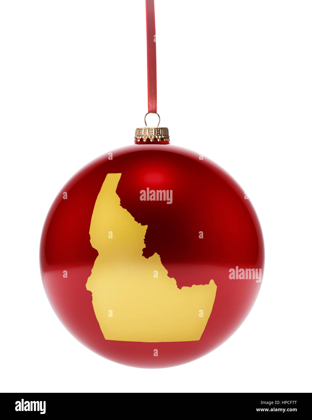 A hanging glossy red bauble with the golden shape of Idaho.(series) Stock Photo