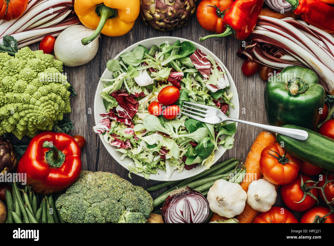 Fresh tasty vegetarian salad with seasonal ingredients surrounded by colorful vegetables, healthy vegetarian eating concept Stock Photo