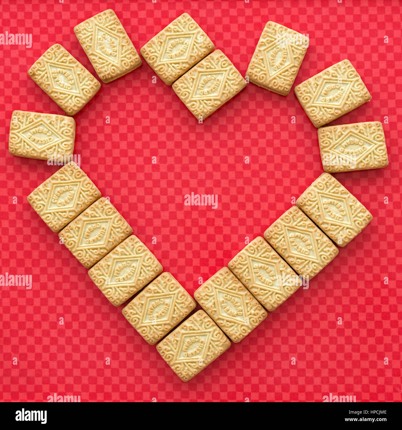 Valentines day love heart made from custard cream biscuits arranged on pink background Stock Photo