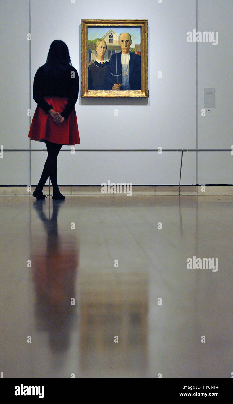 A woman looks at American Gothic by Grant Wood on display during a photocall in the Sackler Galleries at Royal Academy of Arts, London, ahead of the opening of the their America after the Fall: Painting in the 1930s exhibition. Stock Photo