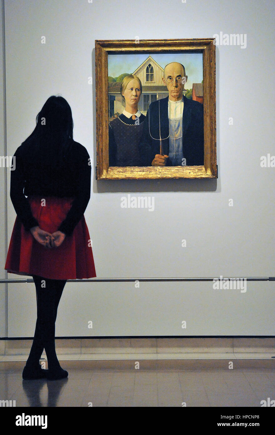 A woman looks at American Gothic by Grant Wood on display during a photocall in the Sackler Galleries at Royal Academy of Arts, London, ahead of the opening of the their America after the Fall: Painting in the 1930s exhibition. Stock Photo
