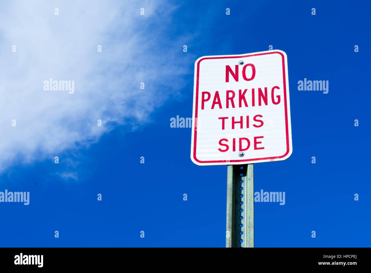 'No parking this side' sign against vibrant blue sky Stock Photo - Alamy