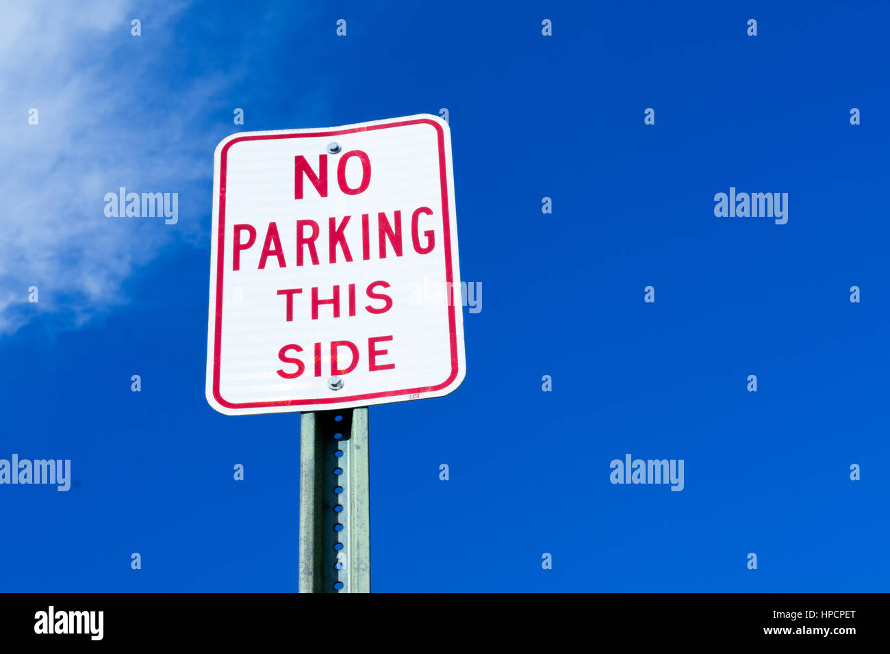 'No parking this side' sign against vibrant blue sky Stock Photo - Alamy
