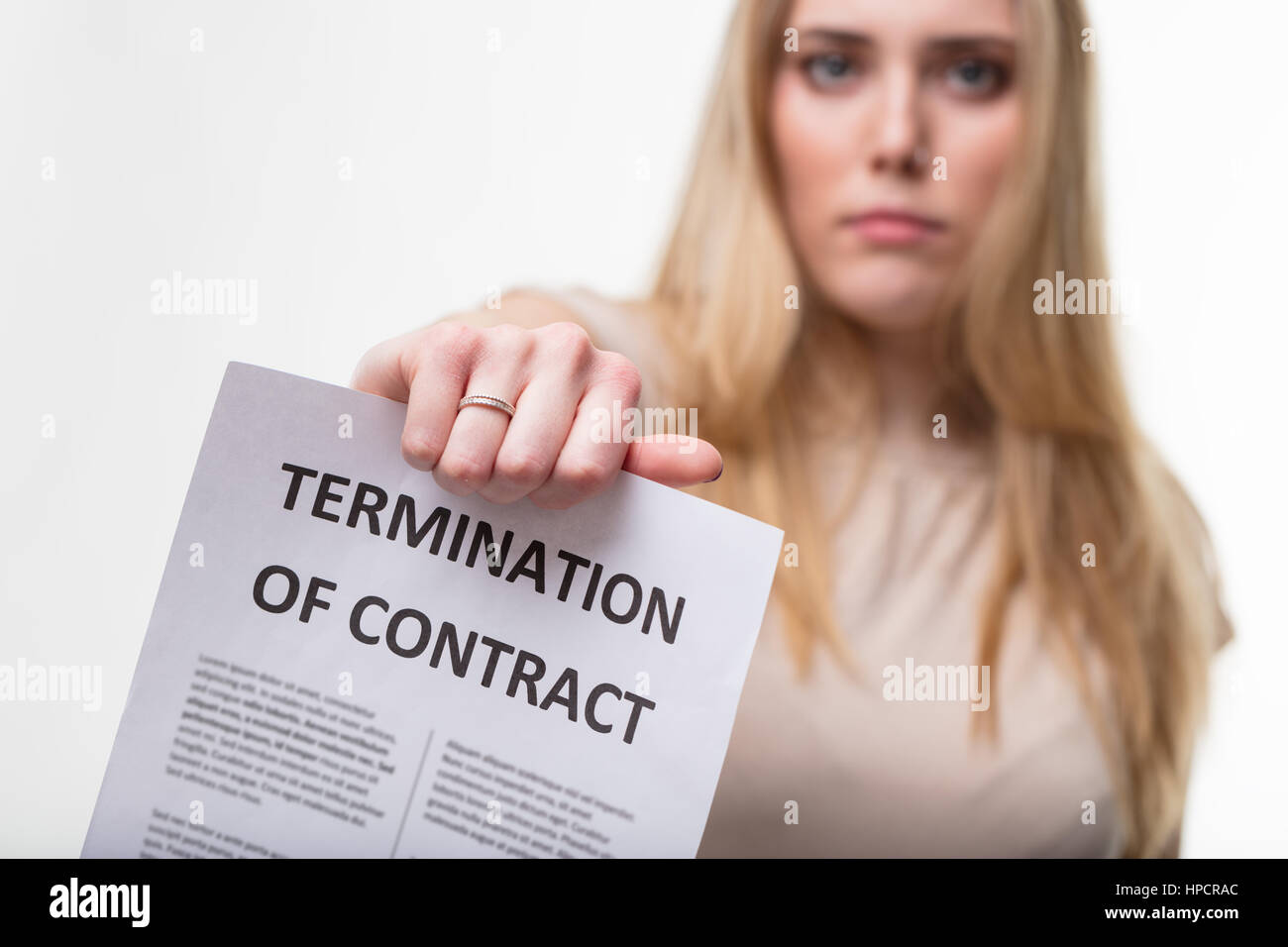 employment termiantion concept, a blonde executive business woman on a white background holding a termination of employment document with wich she's f Stock Photo