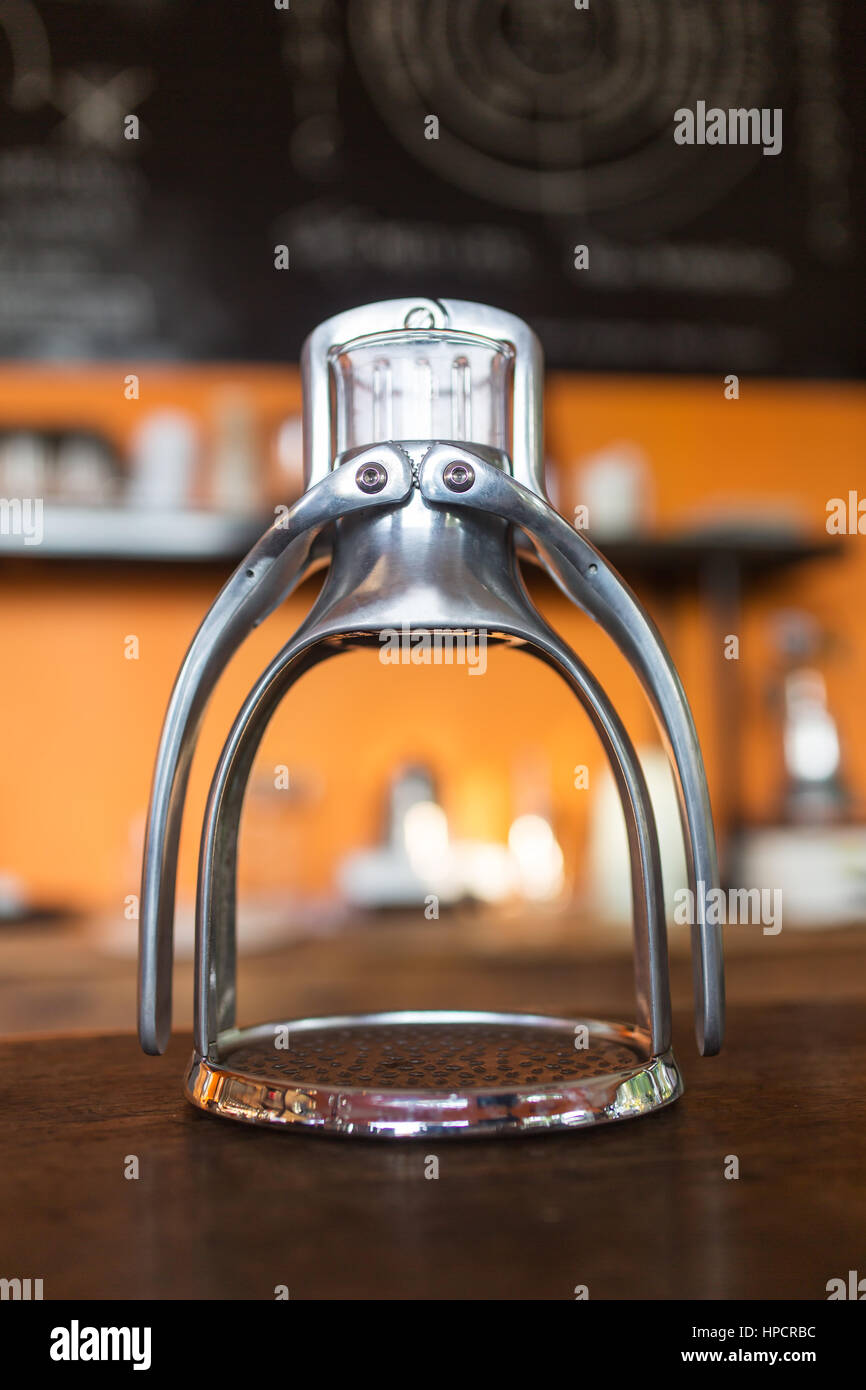 Manual old school espresso maker machine with a cup on wooden table in