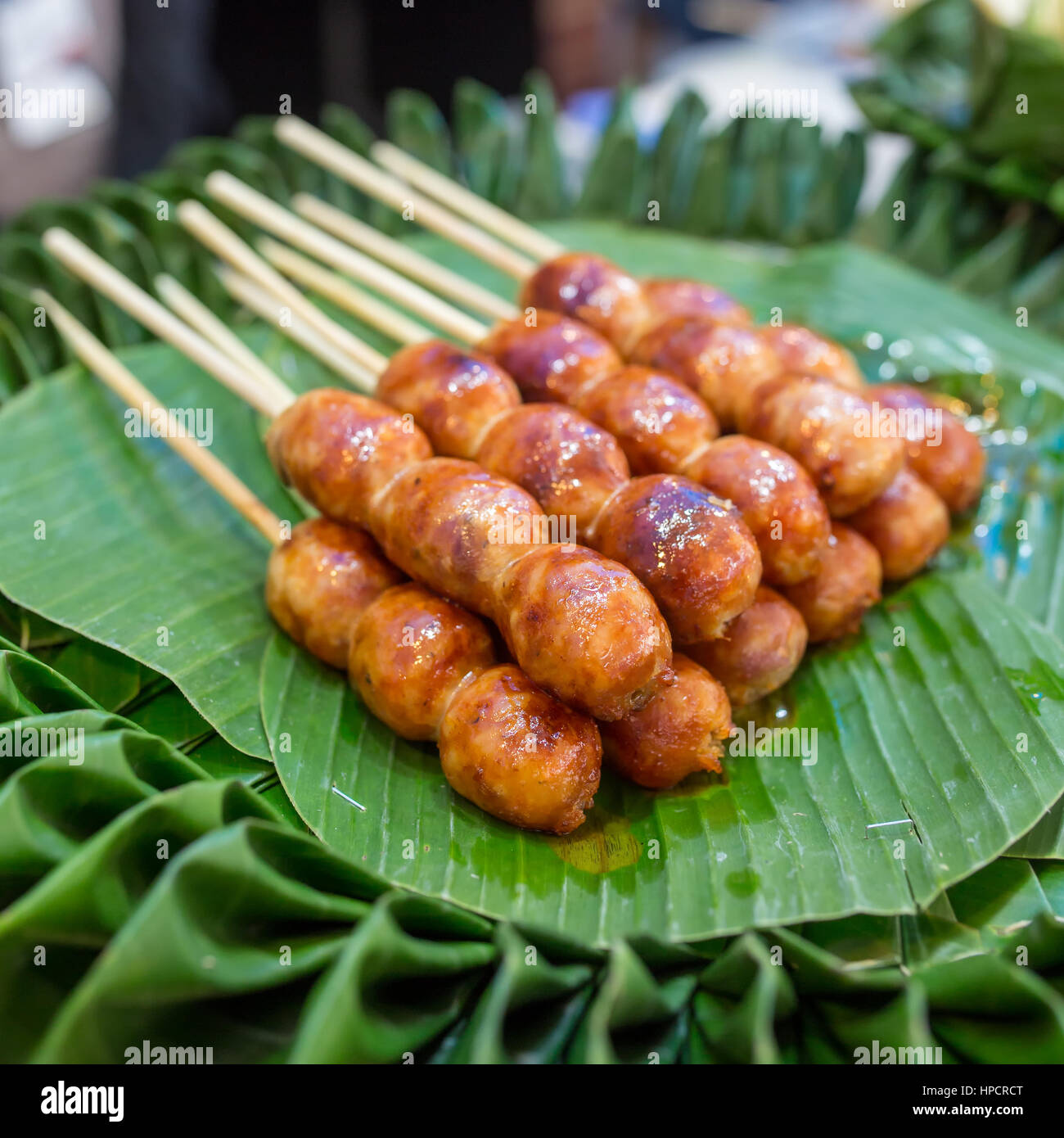 Traditional Thai style grilled Sausages on the banana leaf. Isaan pork meat sausage. Stock Photo