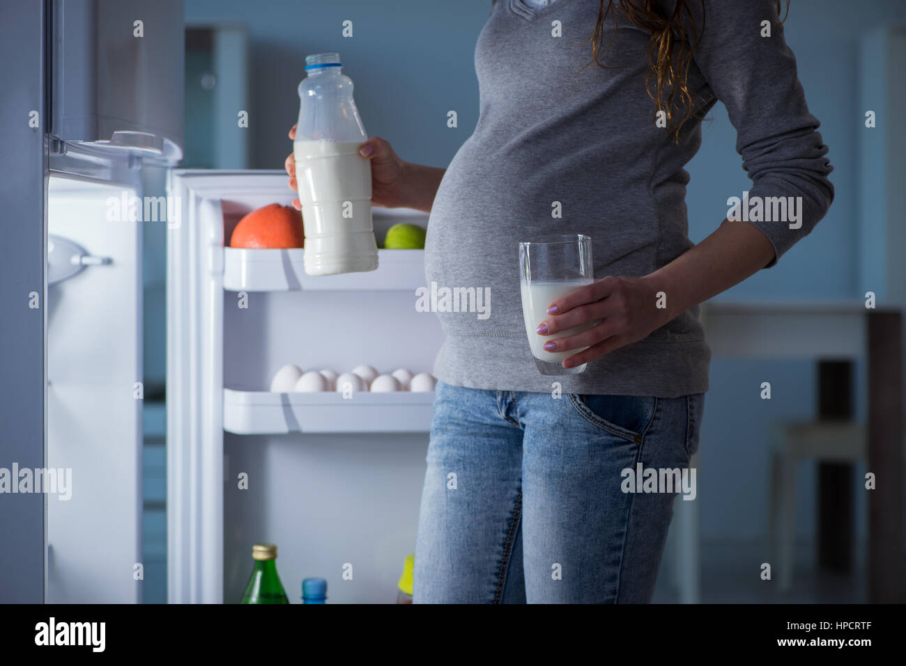 Pregnant woman near fridge looking for food and snacks at night Stock Photo
