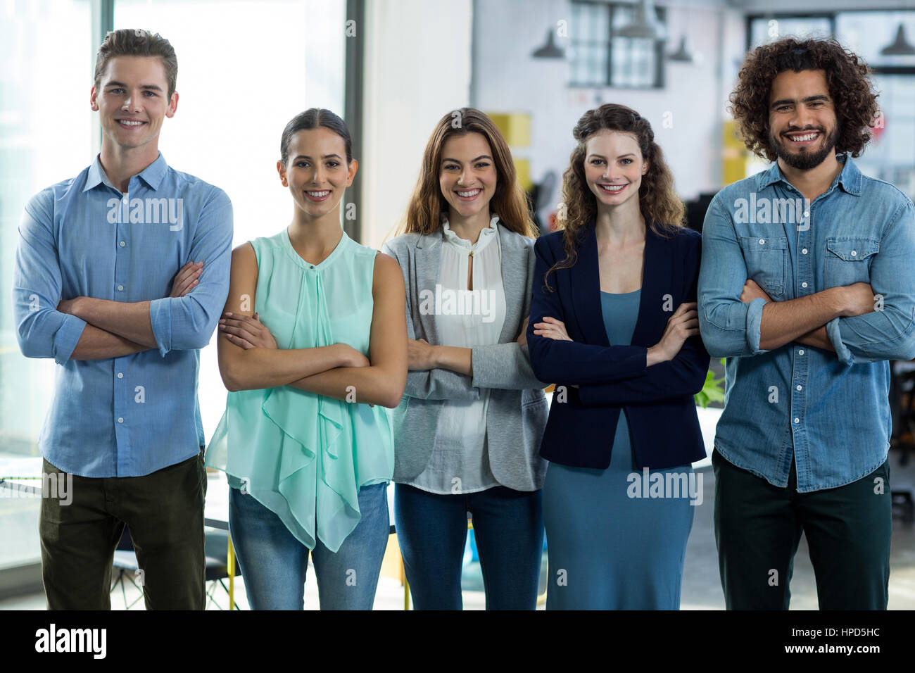 Portrait of smiling business executives standing with arms crossed in ...