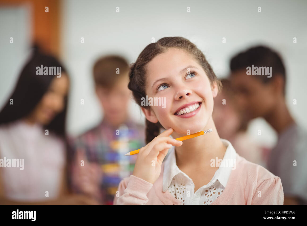Smiling schoolgirl looking up in classroom at school Stock Photo - Alamy