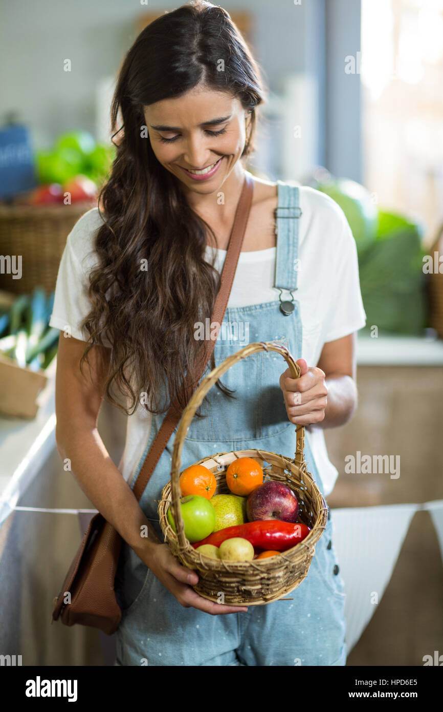Smiling woman holding a basket of fruits in the grocery store Stock ...