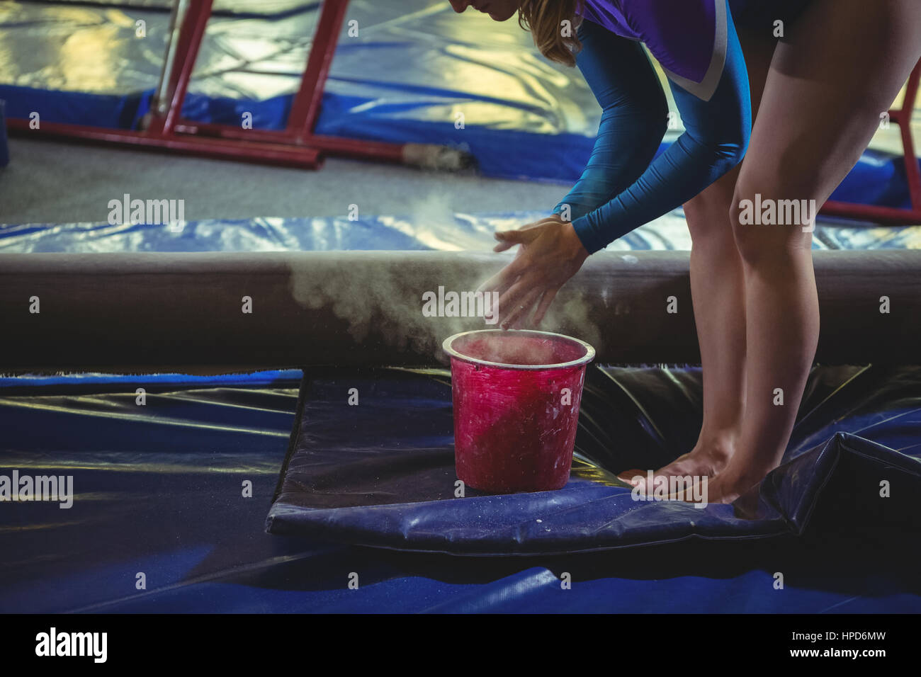 Female gymnast applying chalk powder on her hands before practicing in