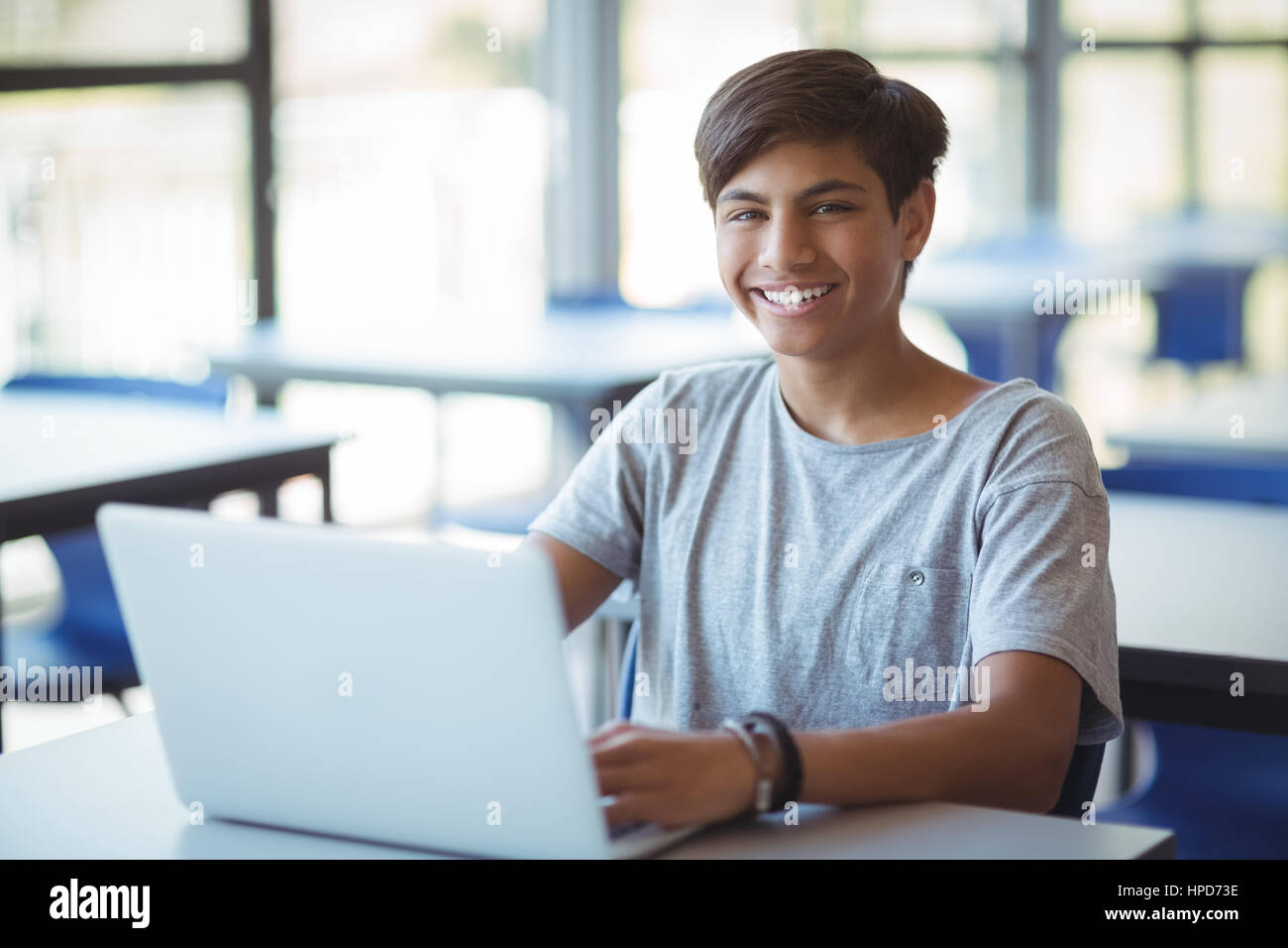 Portrait of happy schoolboy using laptop in classroom at school Stock ...