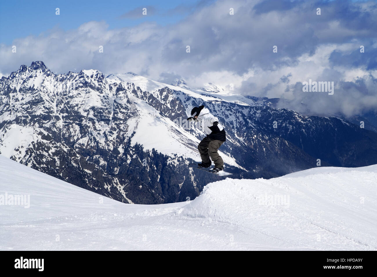 Snowboarder jumping in snow park at ski resort on winter day. Caucasus Mountains, region Dombay. Stock Photo