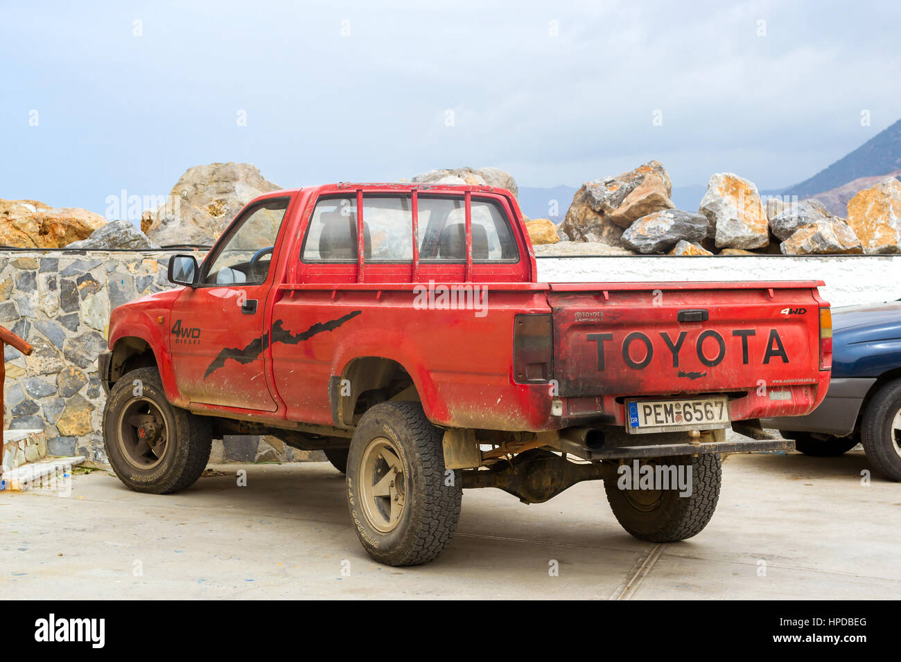 Bali, Greece - April 30, 2016: Old red pickup truck Toyota parked on Mithos beach promenade in sea Harbour of resort village Bali. Light 4wd truck Jap Stock Photo