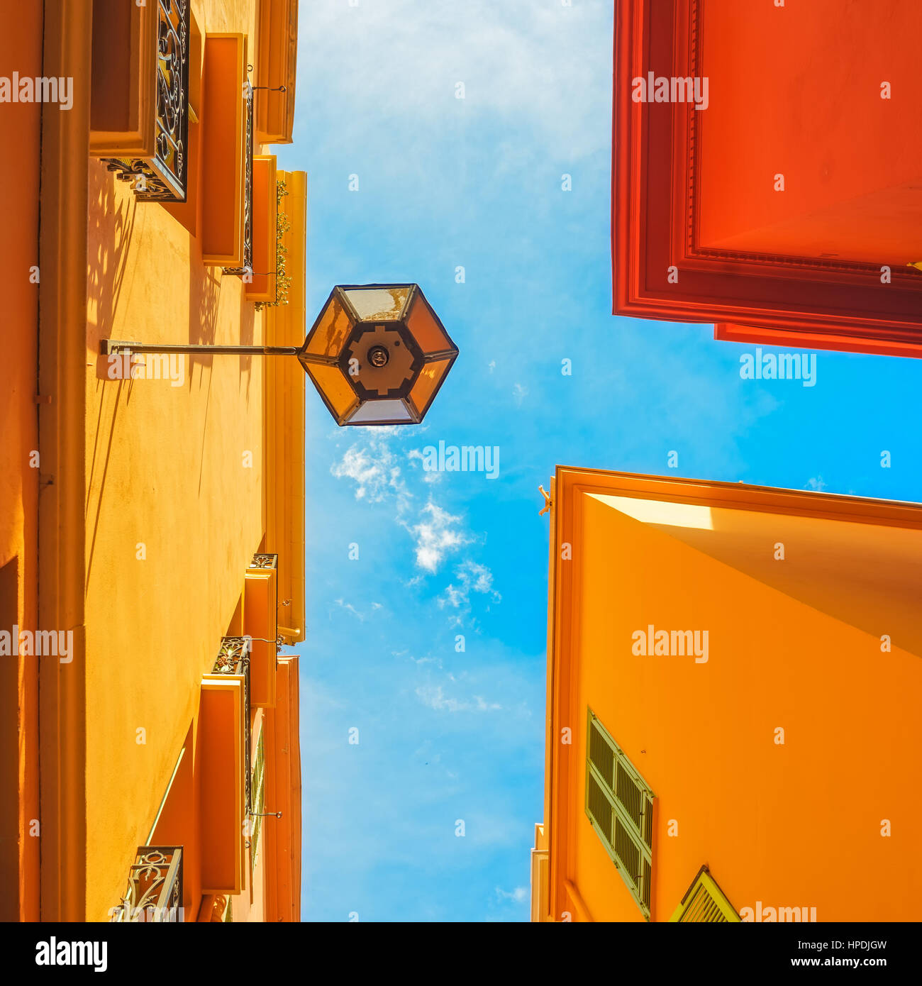 Urban abstract. Street lamp, red yellow orange house facades and blue sky background. Bottom view Stock Photo