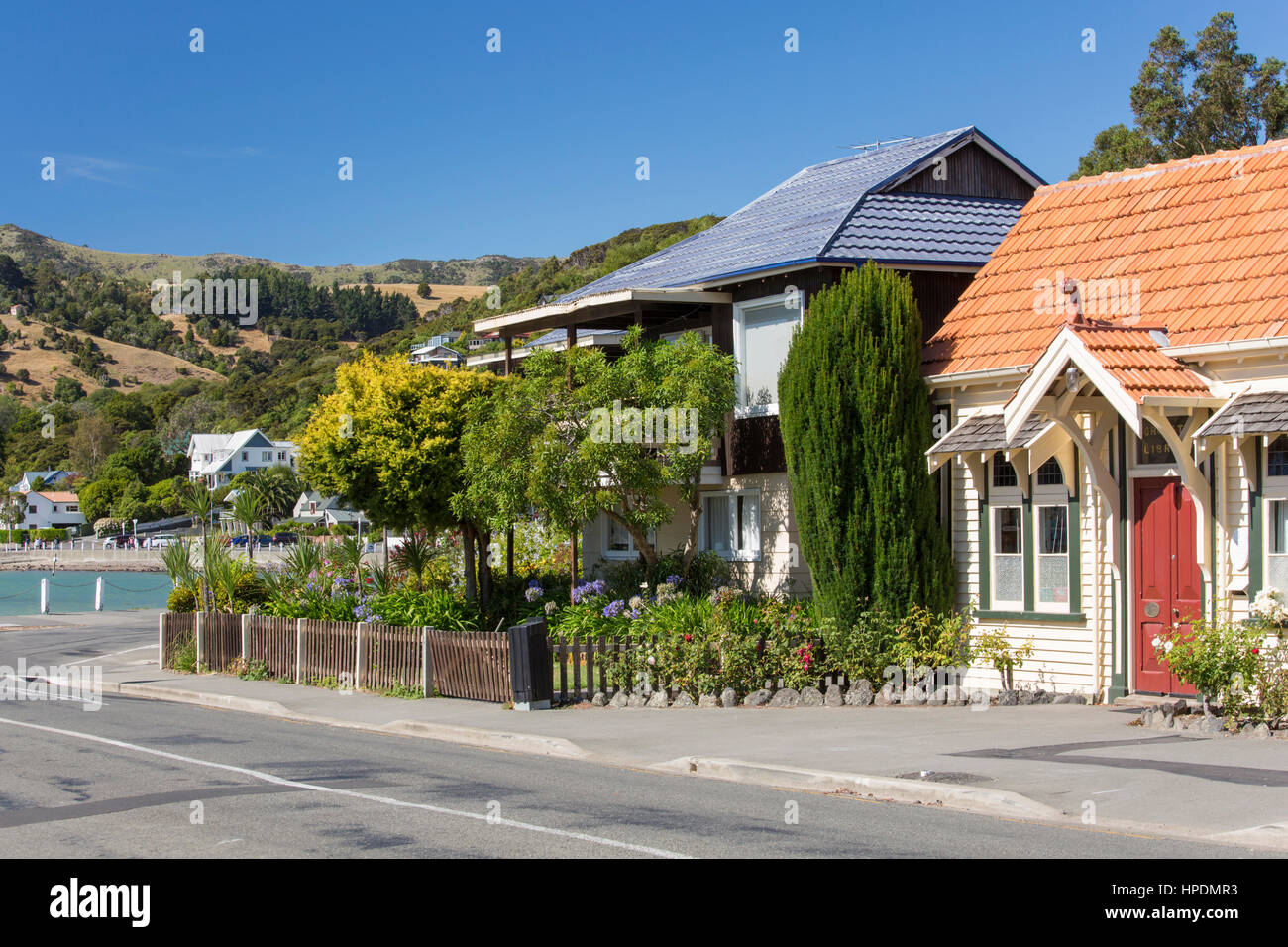 Akaroa, Canterbury, New Zealand. Historic buildings and colourful gardens lining Beach Road. Stock Photo