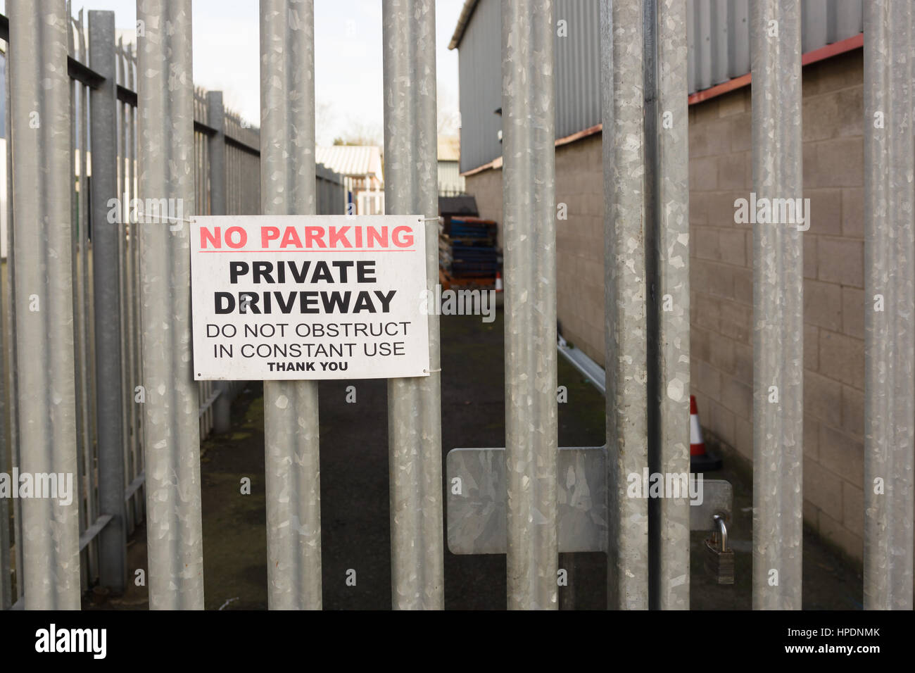 Set of locked security gates with a no parking sign at an industrial or commercial premises Stock Photo