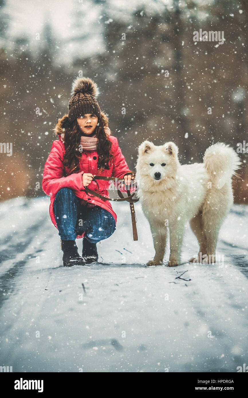 Happy girl with dog in winter forest Stock Photo - Alamy
