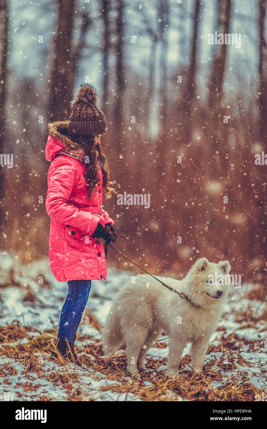 Happy girl with dog in winter forest Stock Photo - Alamy