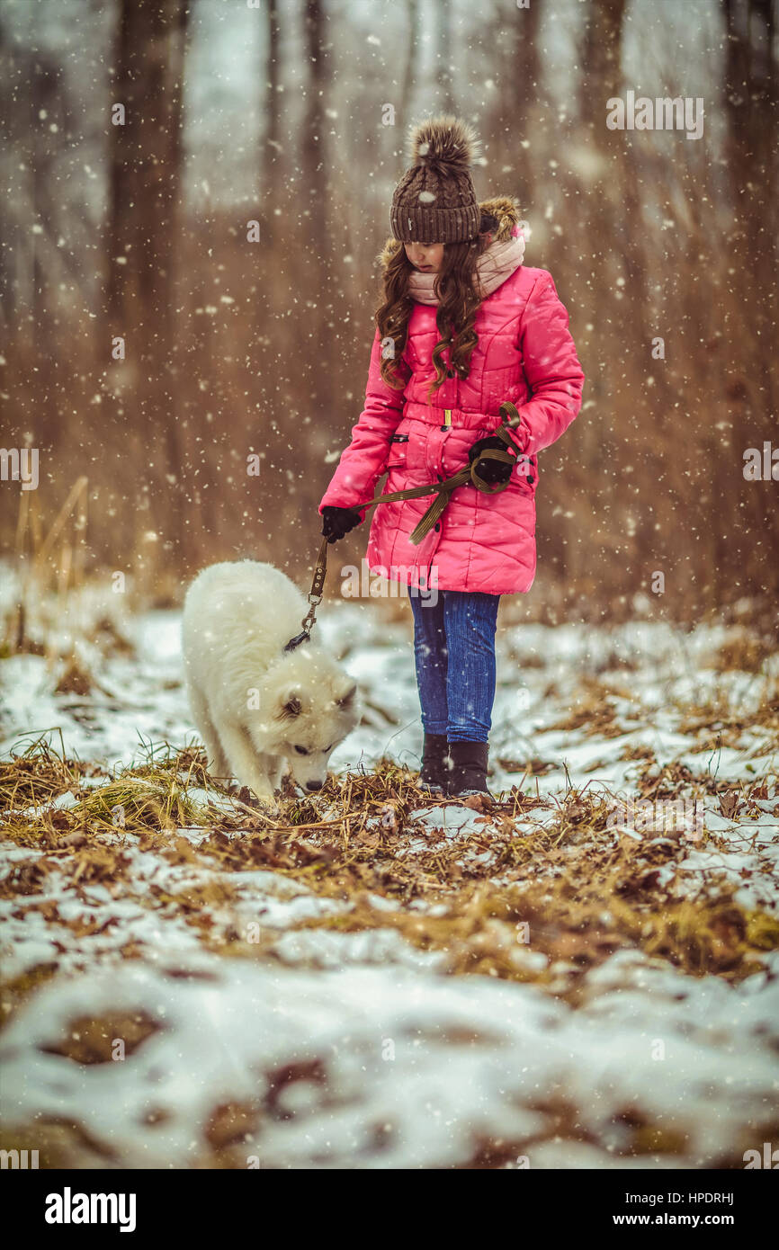Happy girl with dog in winter forest Stock Photo - Alamy