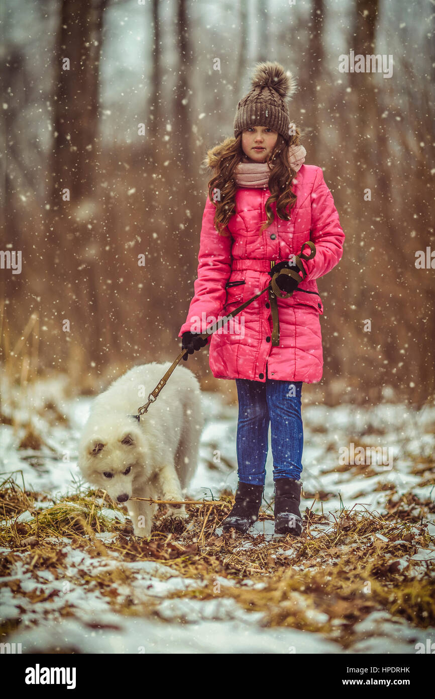 Happy girl with dog in winter forest Stock Photo - Alamy