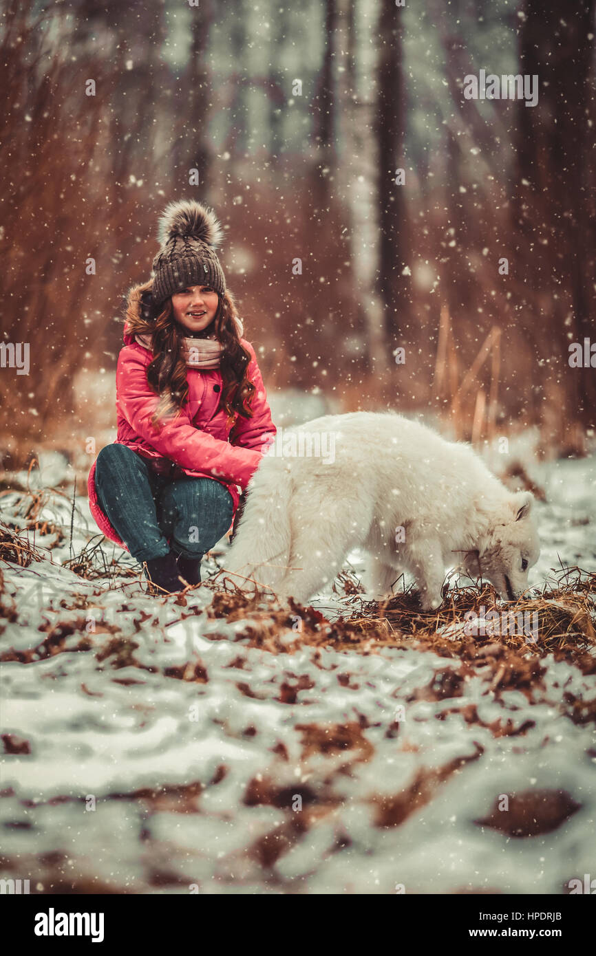 Happy girl with dog in winter forest Stock Photo - Alamy