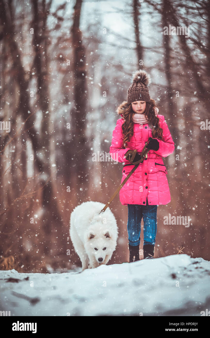 Happy girl with dog in winter forest Stock Photo - Alamy