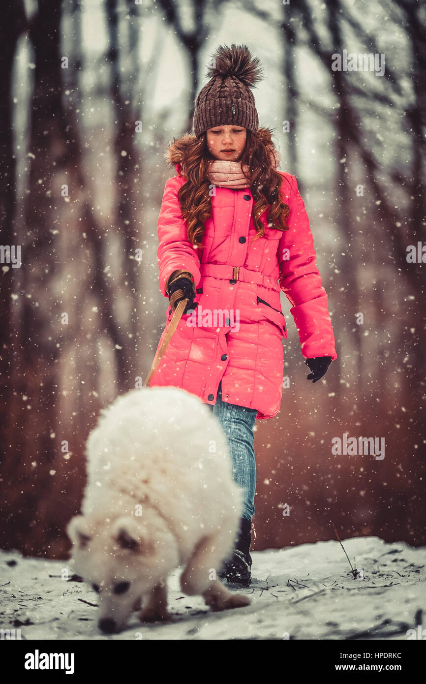 Happy girl with dog in winter forest Stock Photo - Alamy
