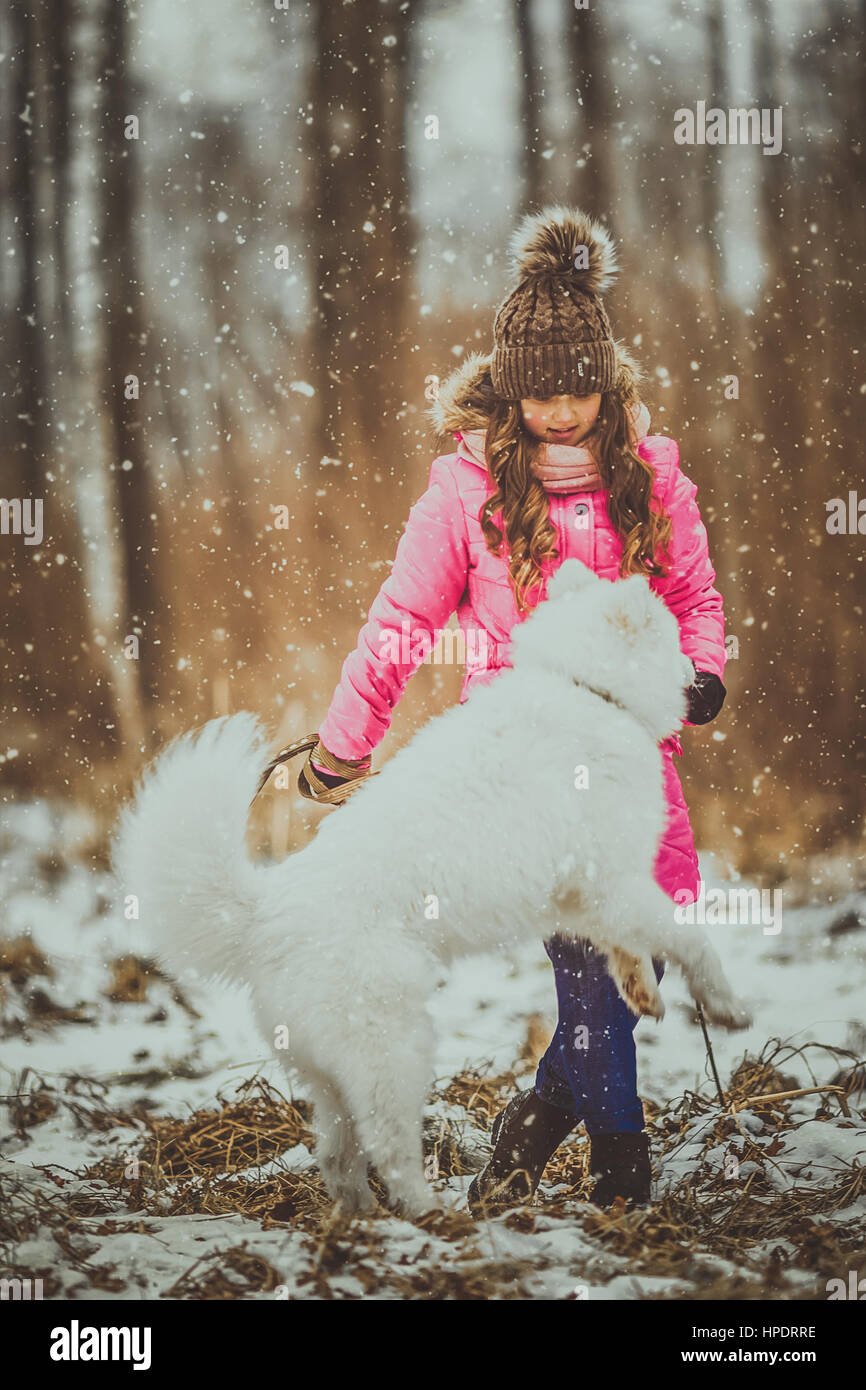 Happy girl with dog in winter forest Stock Photo - Alamy