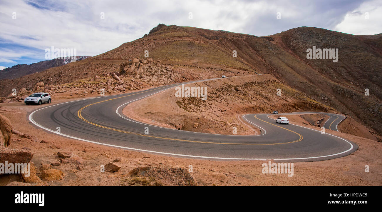 Several cars climbing the long, steep, winding road to the top of Pikes Peak in Colorado. Stock Photo