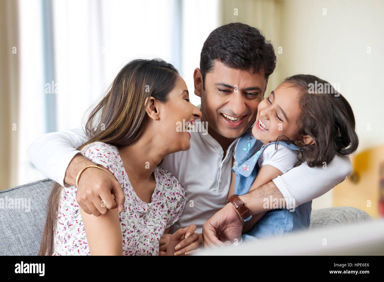 Playful family of three sitting on sofa at home Stock Photo