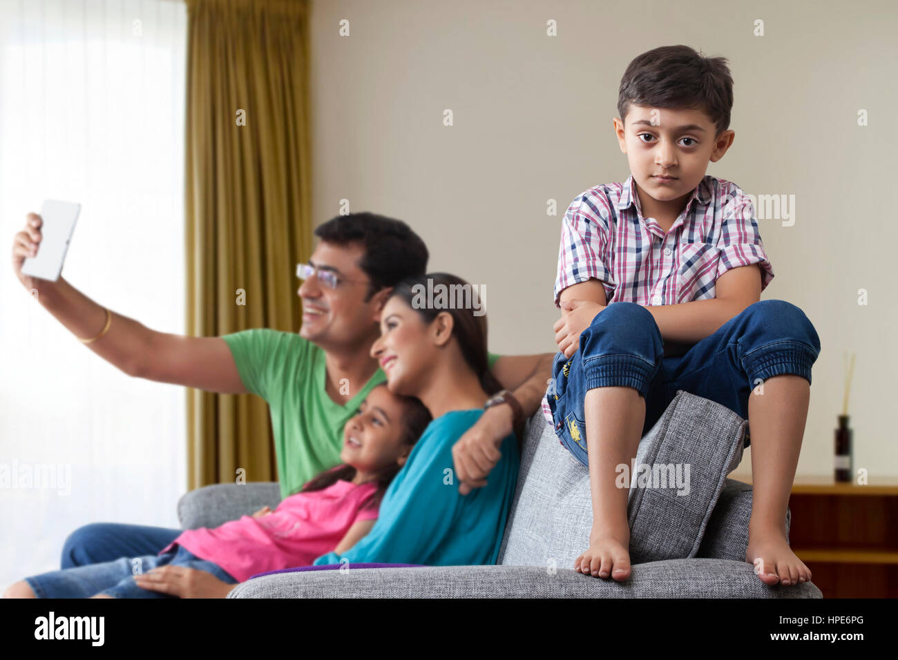 Conflicts with family, Portrait of serious boy with his parents and sister using digital tablet in the background Stock Photo