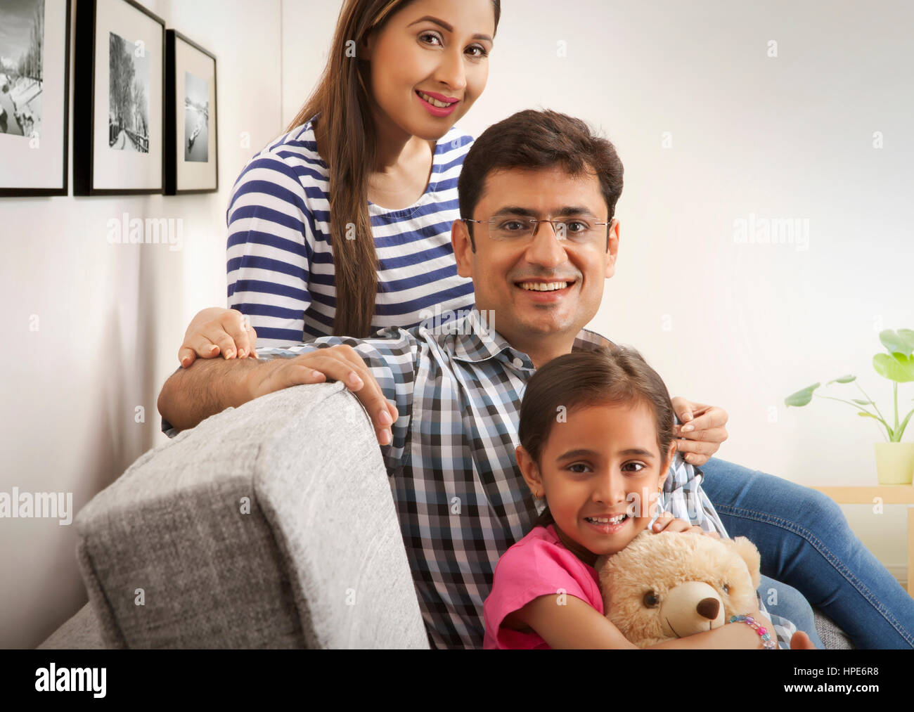 Portrait of happy young family sitting in sofa Stock Photo