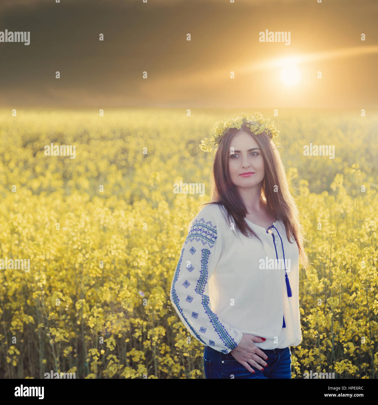 Portrait of a young woman in a rapeseed field. Young girl wearing ...