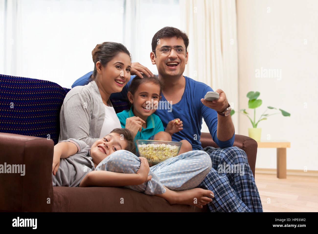 Happy family watching television together and eating popcorn Stock Photo