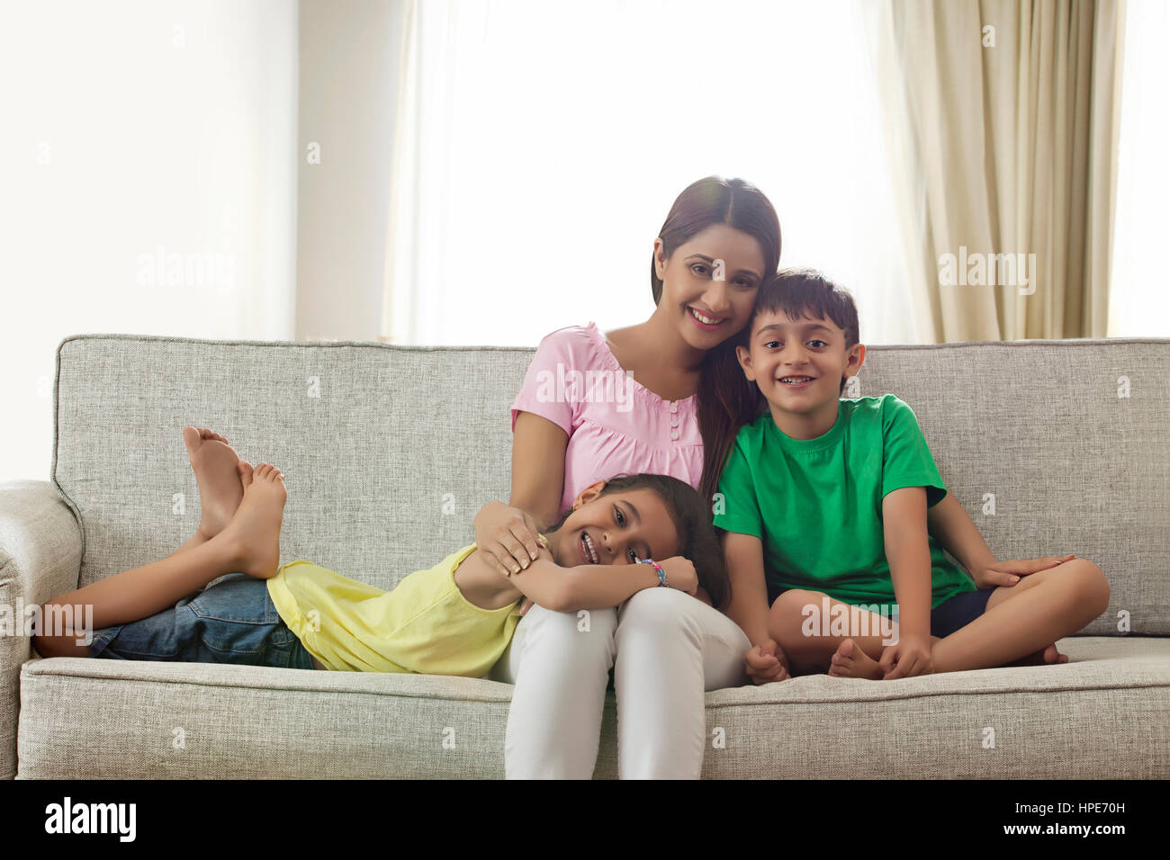 Portrait of happy mother, daughter and son sitting on sofa Stock Photo