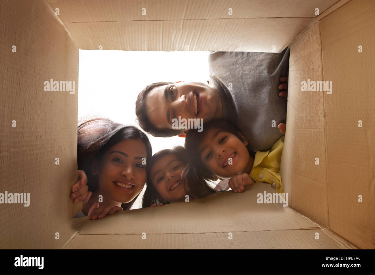 Family looking down at camera through cardboard box Stock Photo