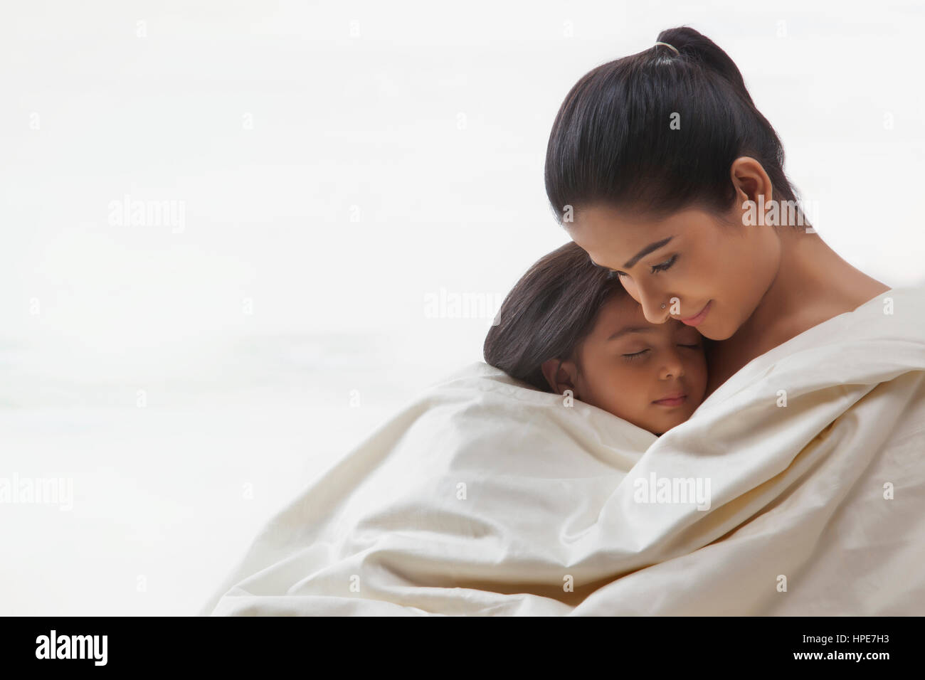 Mother and daughter wrapped in a blanket Stock Photo