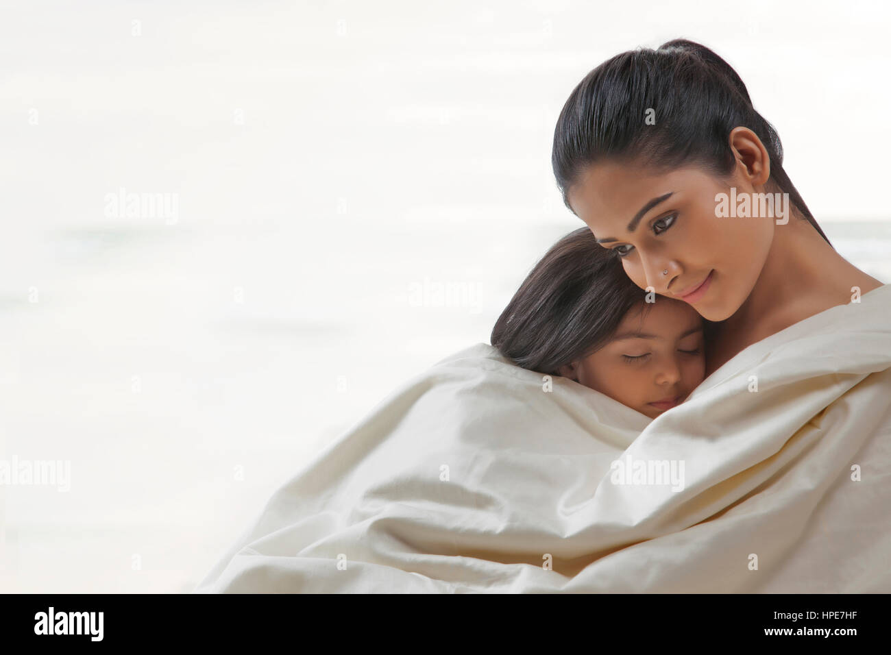 Mother and daughter wrapped in a blanket Stock Photo