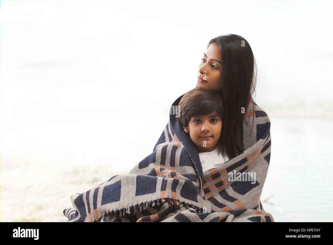 Portrait of smiling son wrapped in blanket with mother Stock Photo