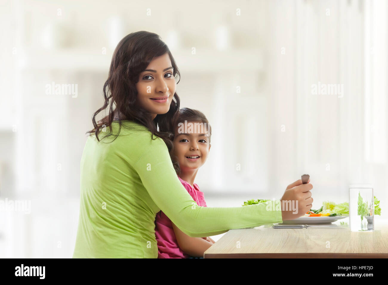 Young mother and daughter eating salad in the kitchen Stock Photo