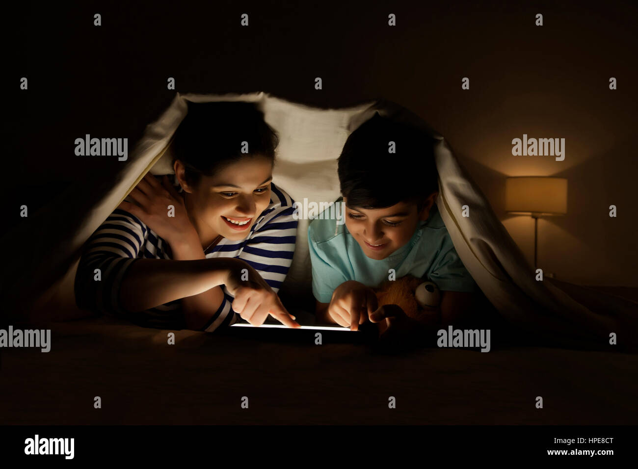 Mother and son using digital tablet together lying in bed under the blanket Stock Photo Alamy