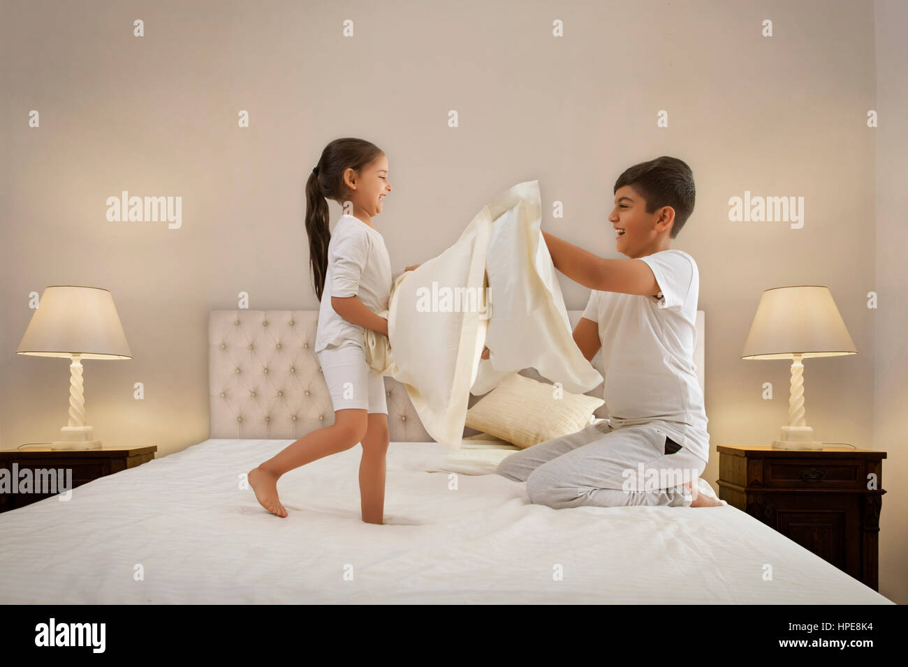 Brother and sister having a pillow fight in bed Stock Photo