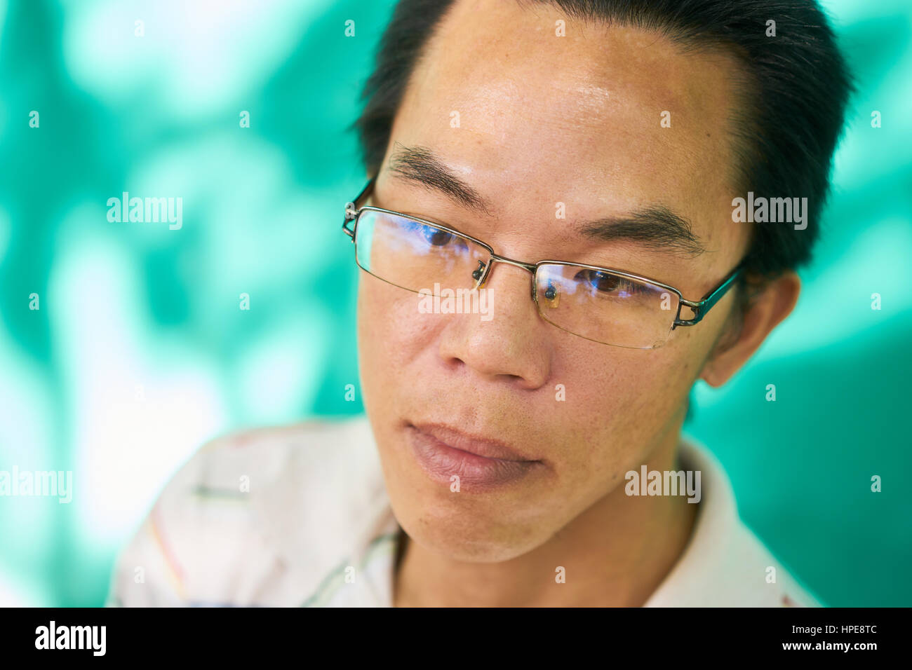 Real Cuban people with emotions and feelings, portrait of sad young asian-latino man with glasses from Havana, Cuba looking at camera. Multiethnic per Stock Photo