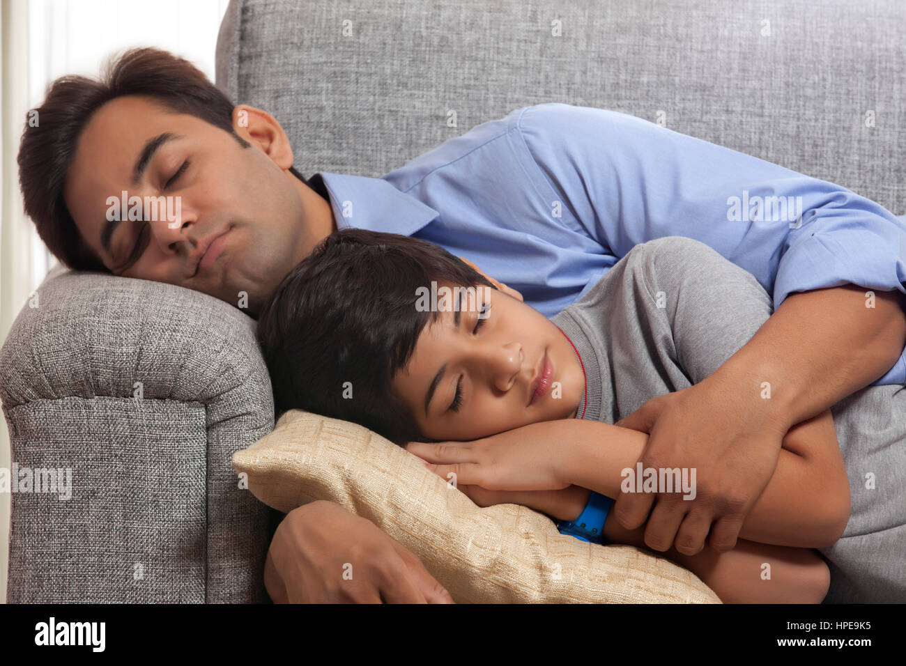Father and son napping on sofa Stock Photo